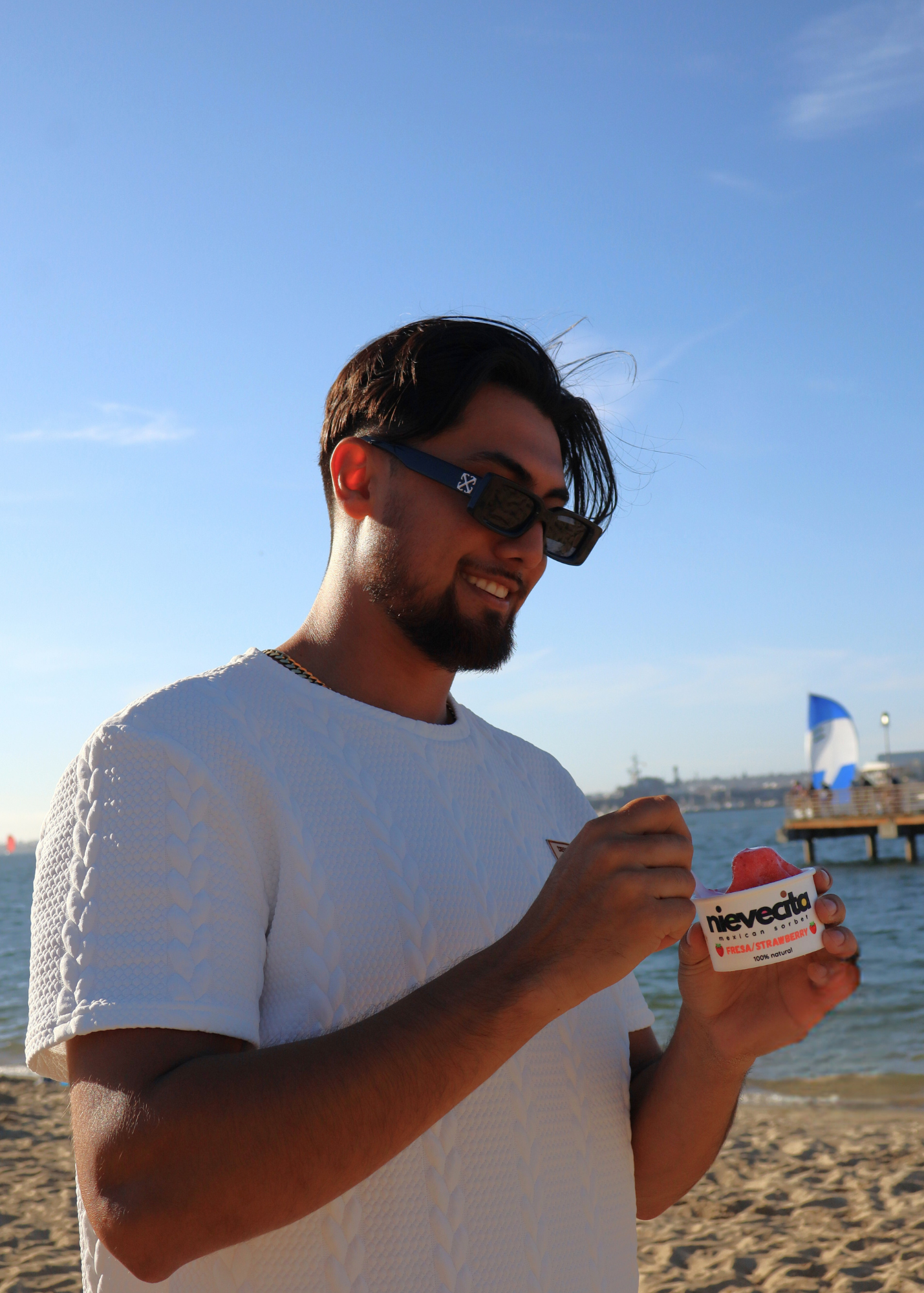 Man on a beach holding a container of Neveco ice cream. san diego